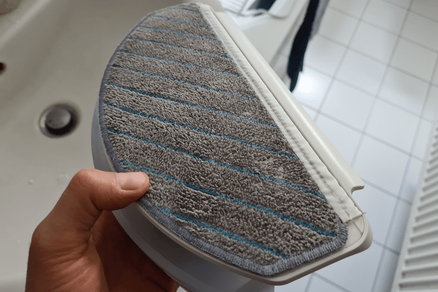 Dreckiger Wischmopp des Ecovacs Deebot T10 wird in den Händen gehalten.